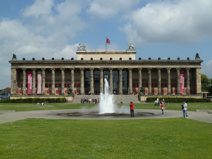 a large building with fountains and people in front