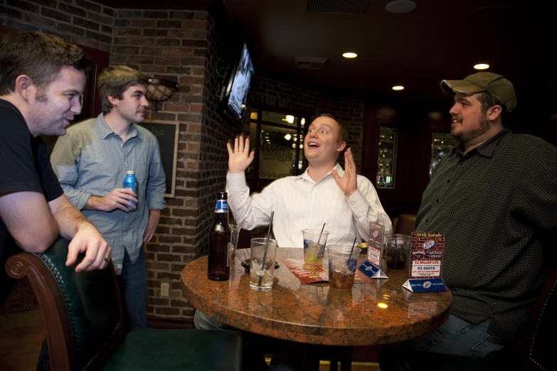 three men are sitting at a table with drinks