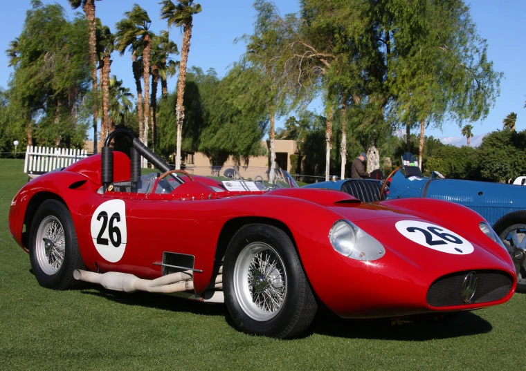 a red sports car parked in a park near palm trees