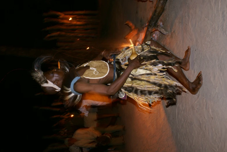 a man dressed in feathers holds his sword and dances