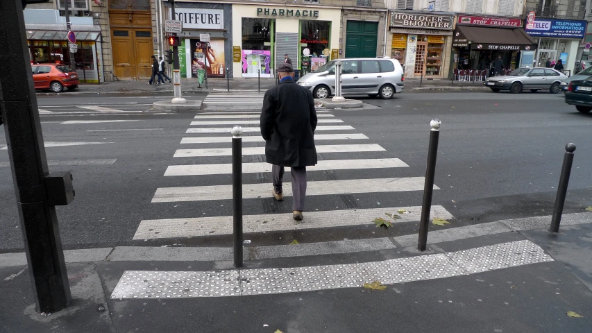 a man standing in front of a crosswalk with poles