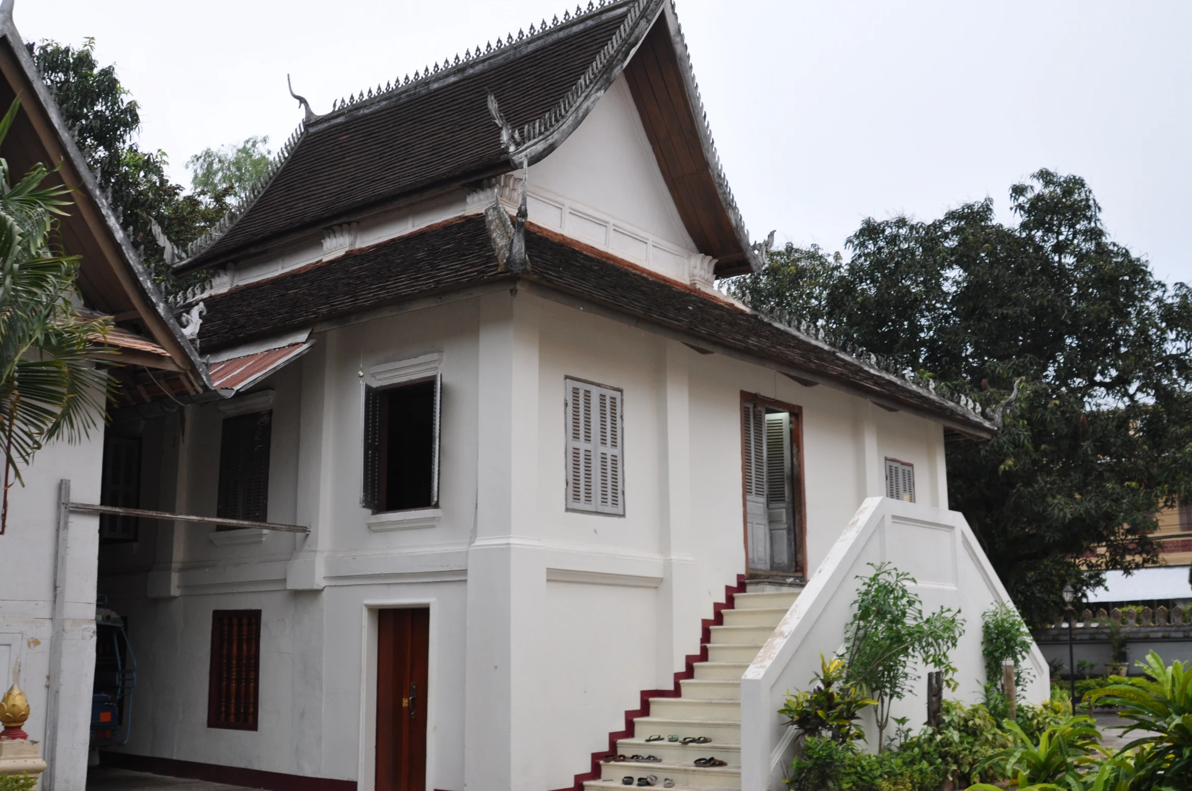 a white building with steps to it near bushes and trees