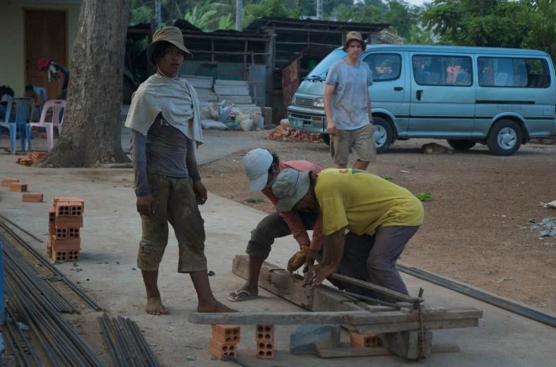 three men standing next to each other working on some wooden pieces