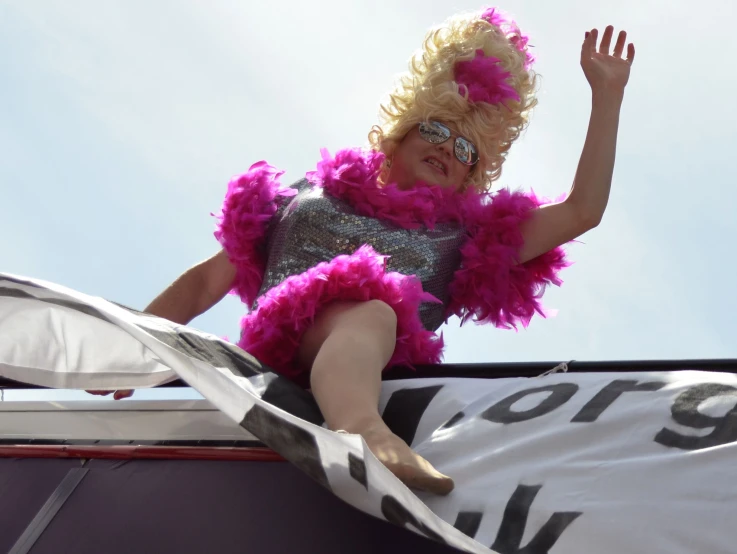 the little girl in the feather boa is sitting on the top of a car