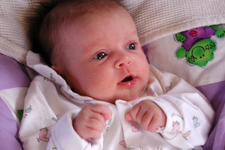 a baby lying down in pajamas with a stuffed animal on the back