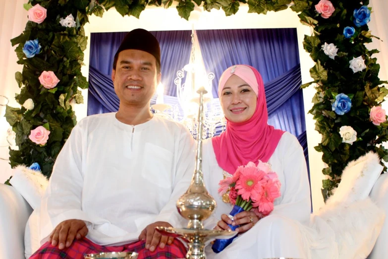 man and woman posing with trophy in front of flower display