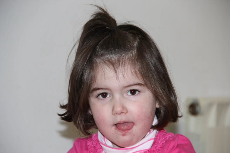 a young child with her tongue out, looking to the camera
