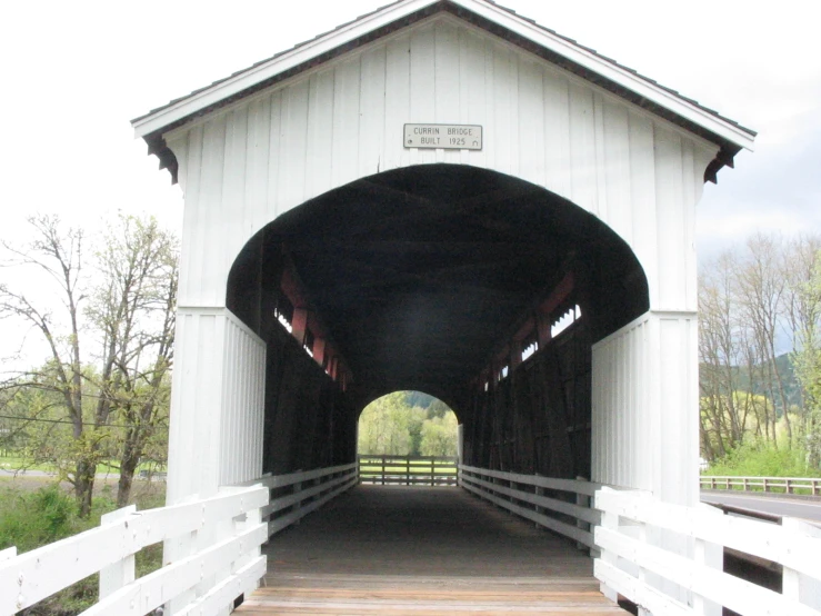 a white covered bridge with lots of trees and grass