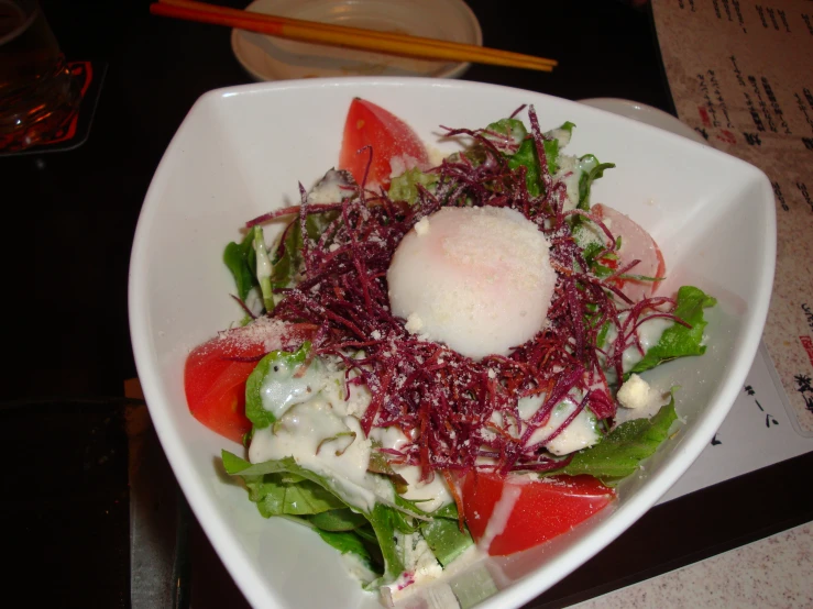 a salad with red and green toppings in a white bowl