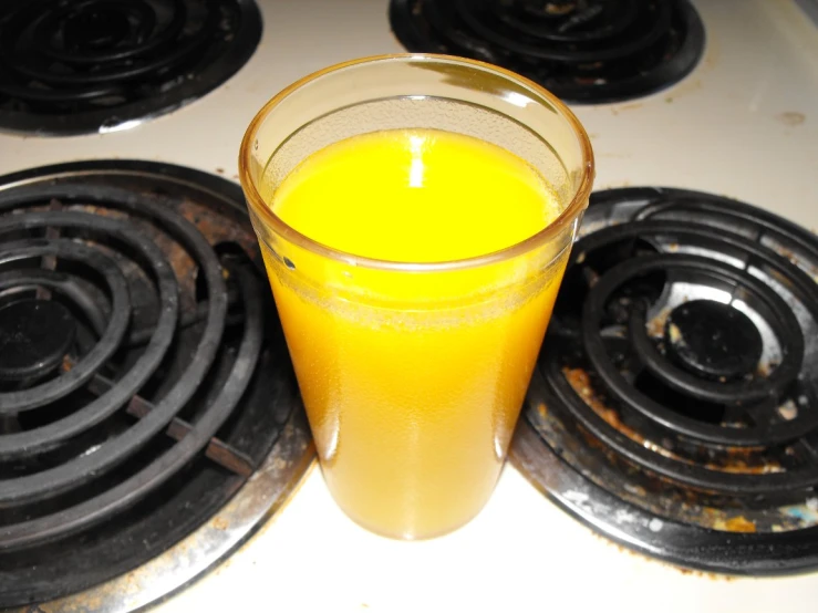 a cup of orange juice on top of stove
