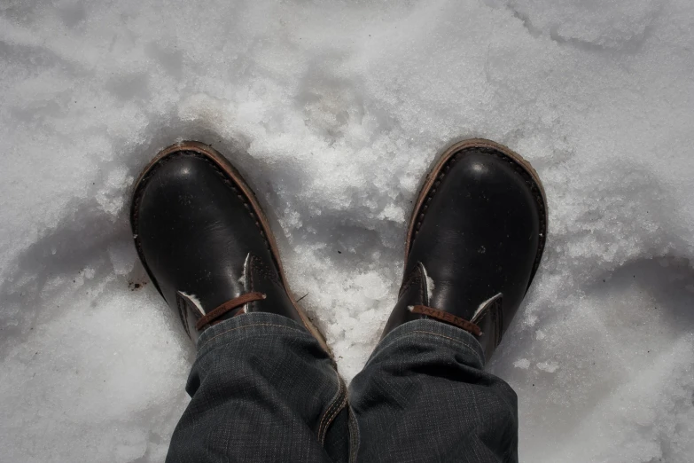 person standing in snow on their shoes with a pair of shoes on