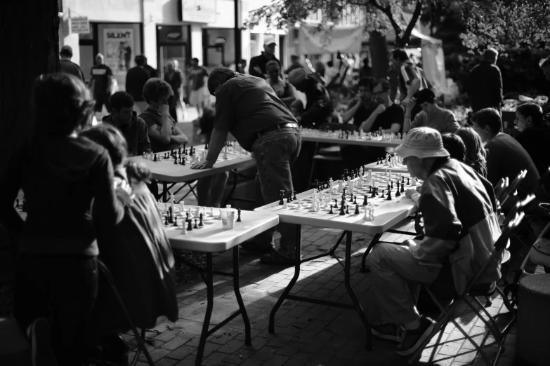 a black and white po of people sitting at tables with chess game on the table