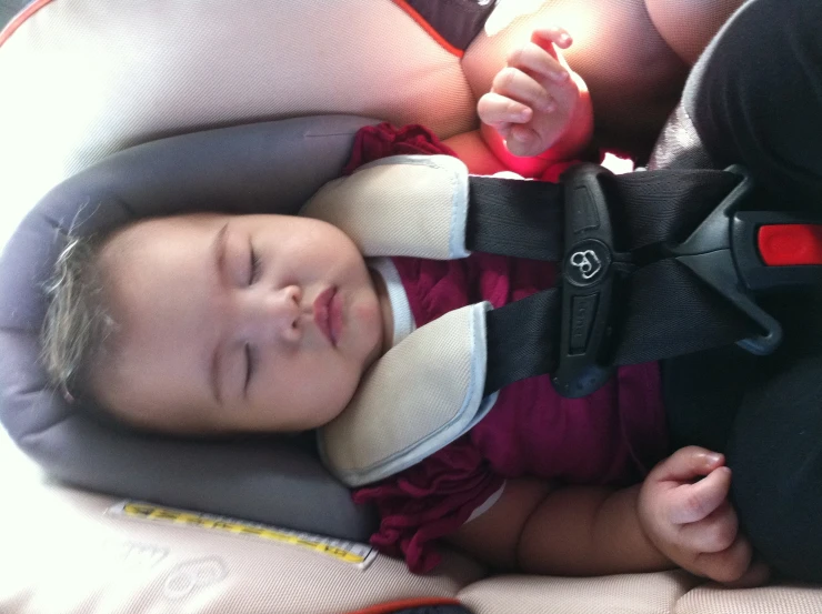 a little child sleeping in a car seat