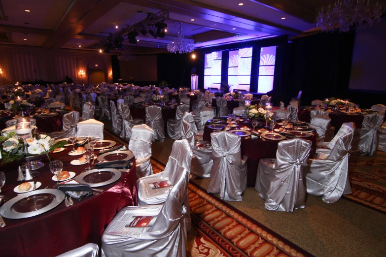 a room full of banquet tables and chairs with silver dd cloths