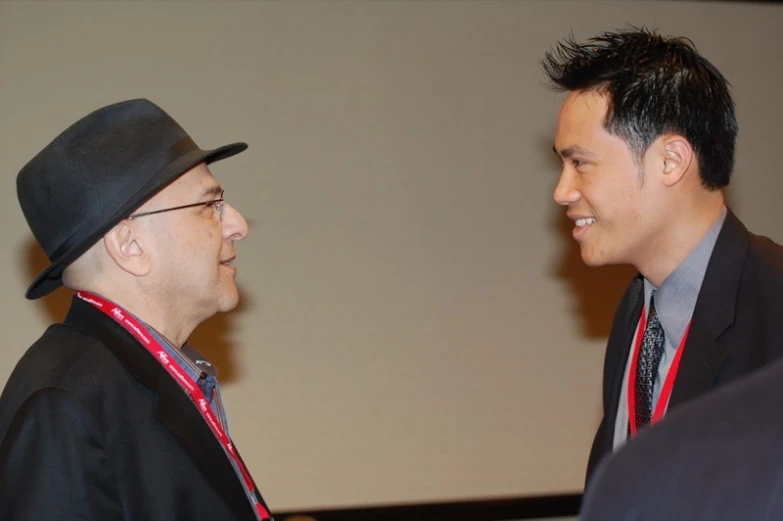 two men wearing suits and hats talk together