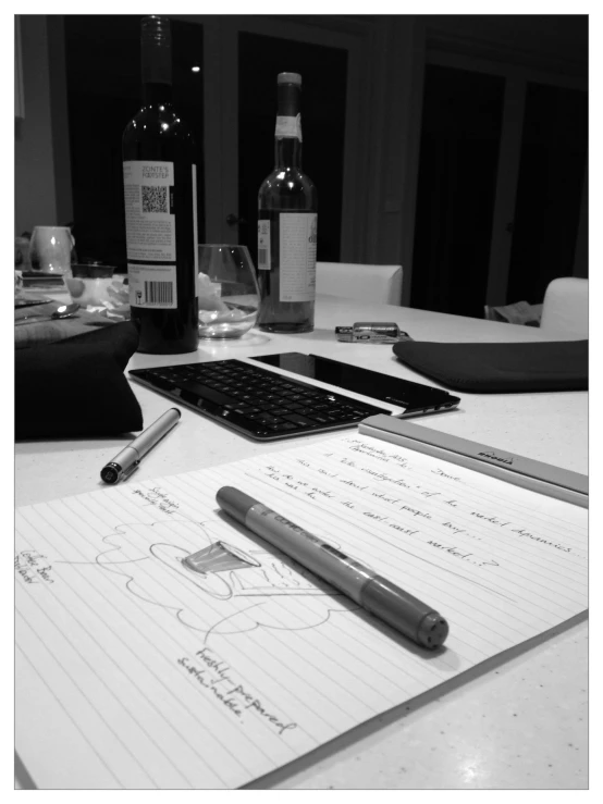 a pen, ruler, bottle and wine on a desk