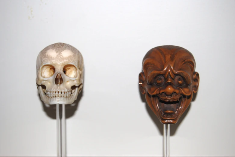 two wooden masks are in a row, one for men and one for women