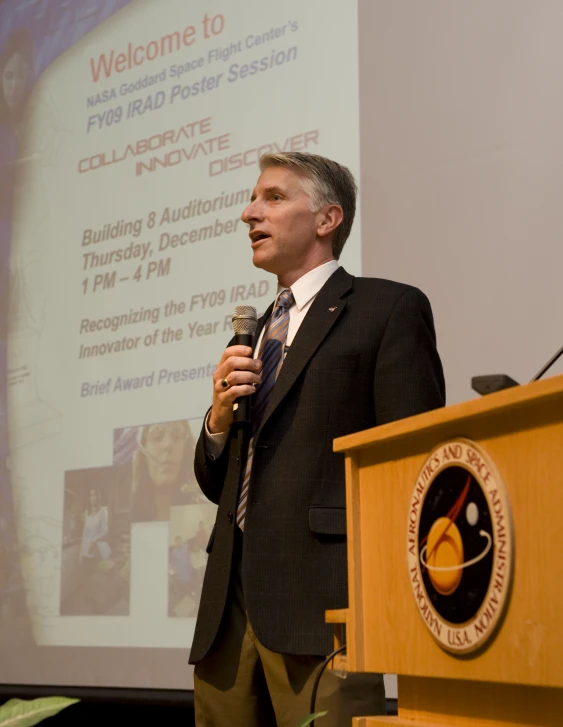 a man in a business suit is speaking into a microphone