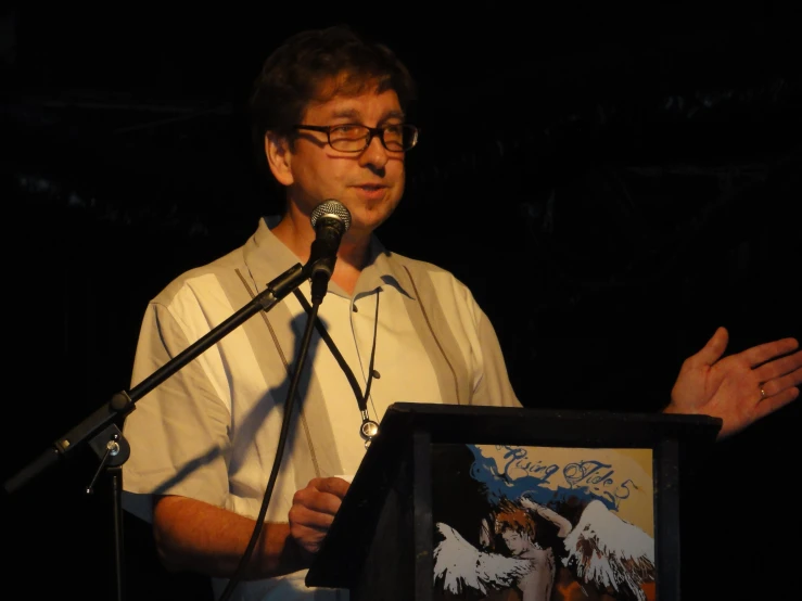 a man wearing glasses stands at a podium and speaks