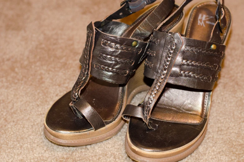 a pair of shoes on a floor with a pair of sneakers hanging from them