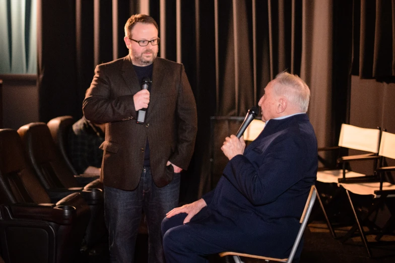 a man talking into a microphone while standing in front of other men