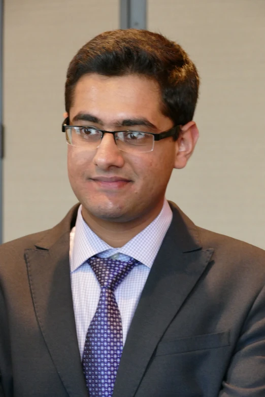 a man wearing glasses and a suit stands behind him