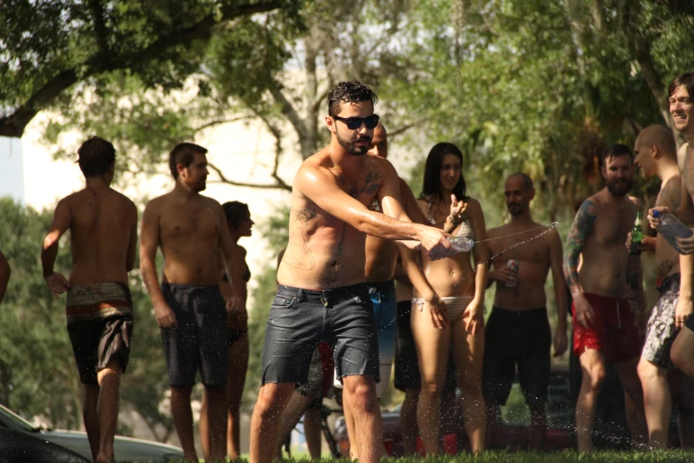 a group of shirtless young people play frisbee in the sun