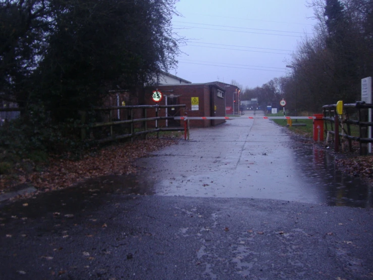 a wet and empty street with houses in the distance