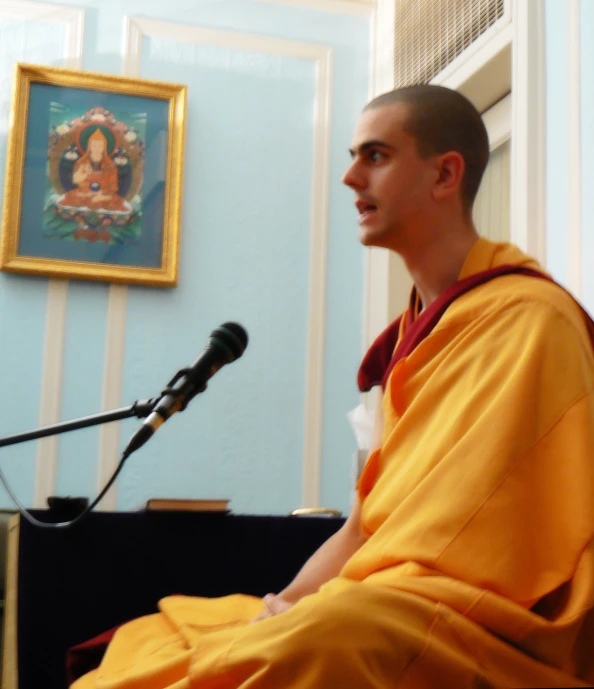 a monk sits in front of a microphone