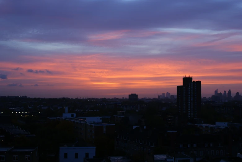 a cloudy sunset over the city and trees