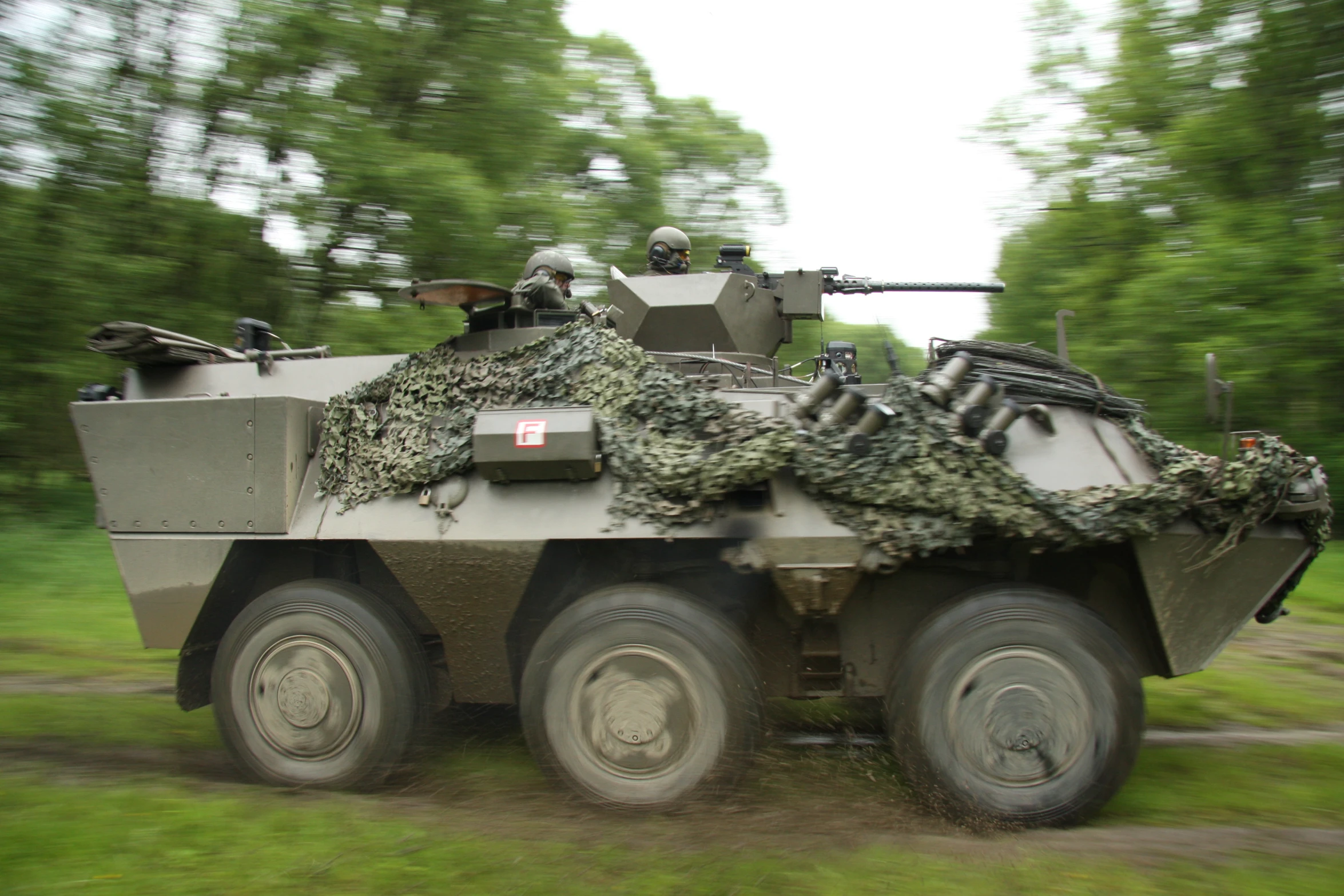 an army armored vehicle with camouflage going by