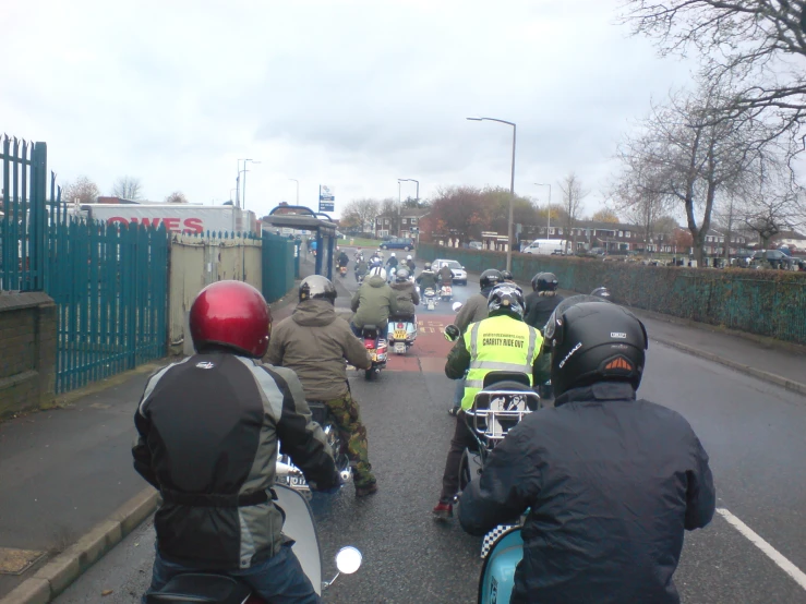 many motorcyclists with helmets and jackets driving down the road