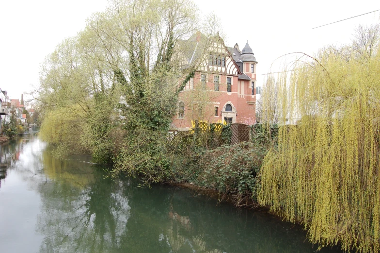 an old red brick building on the corner of a river