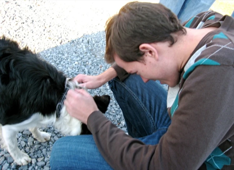 a young man petting a dog with it's tongue