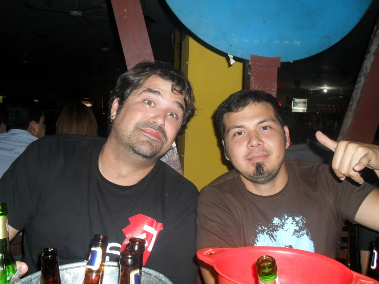 two men sit at a table with beer bottles