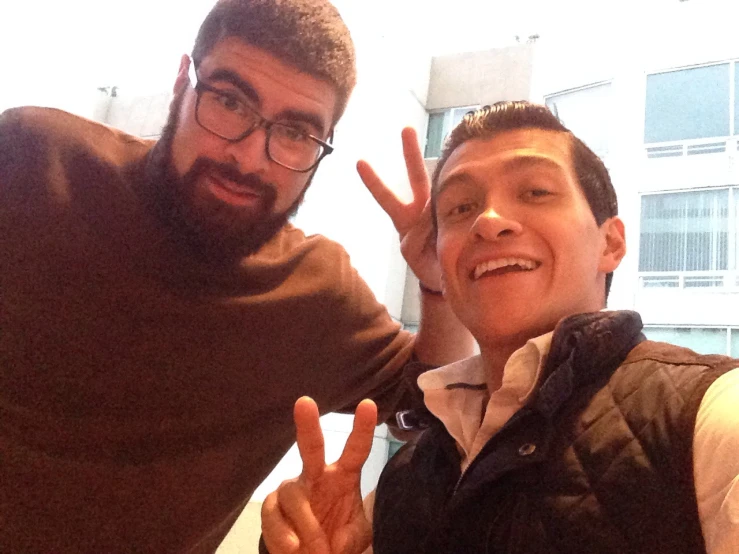 two young men posing for the camera with peace fingers in front of them