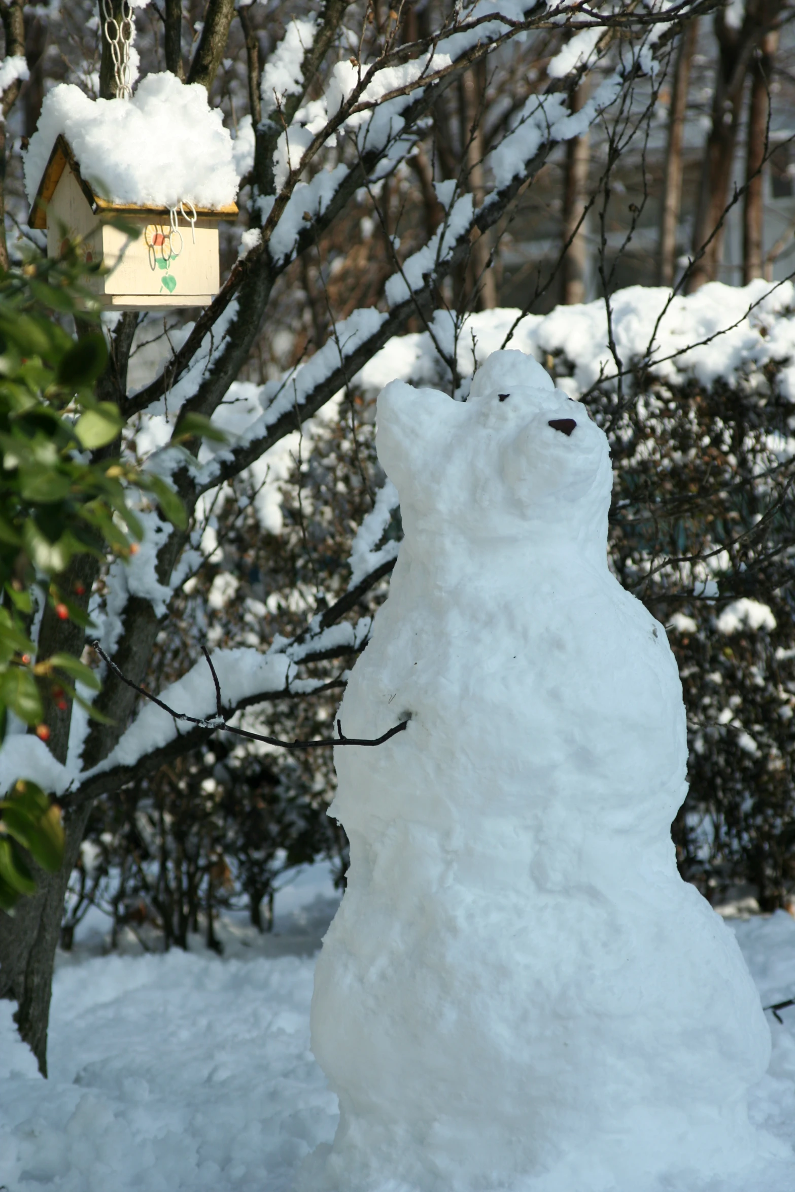 snowman made from nches and ground and hanging from a wire