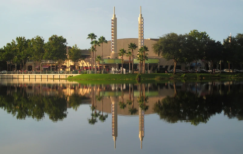 a large water way reflecting a building surrounded by palm trees