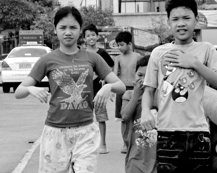 three boys walk through the street with skateboards