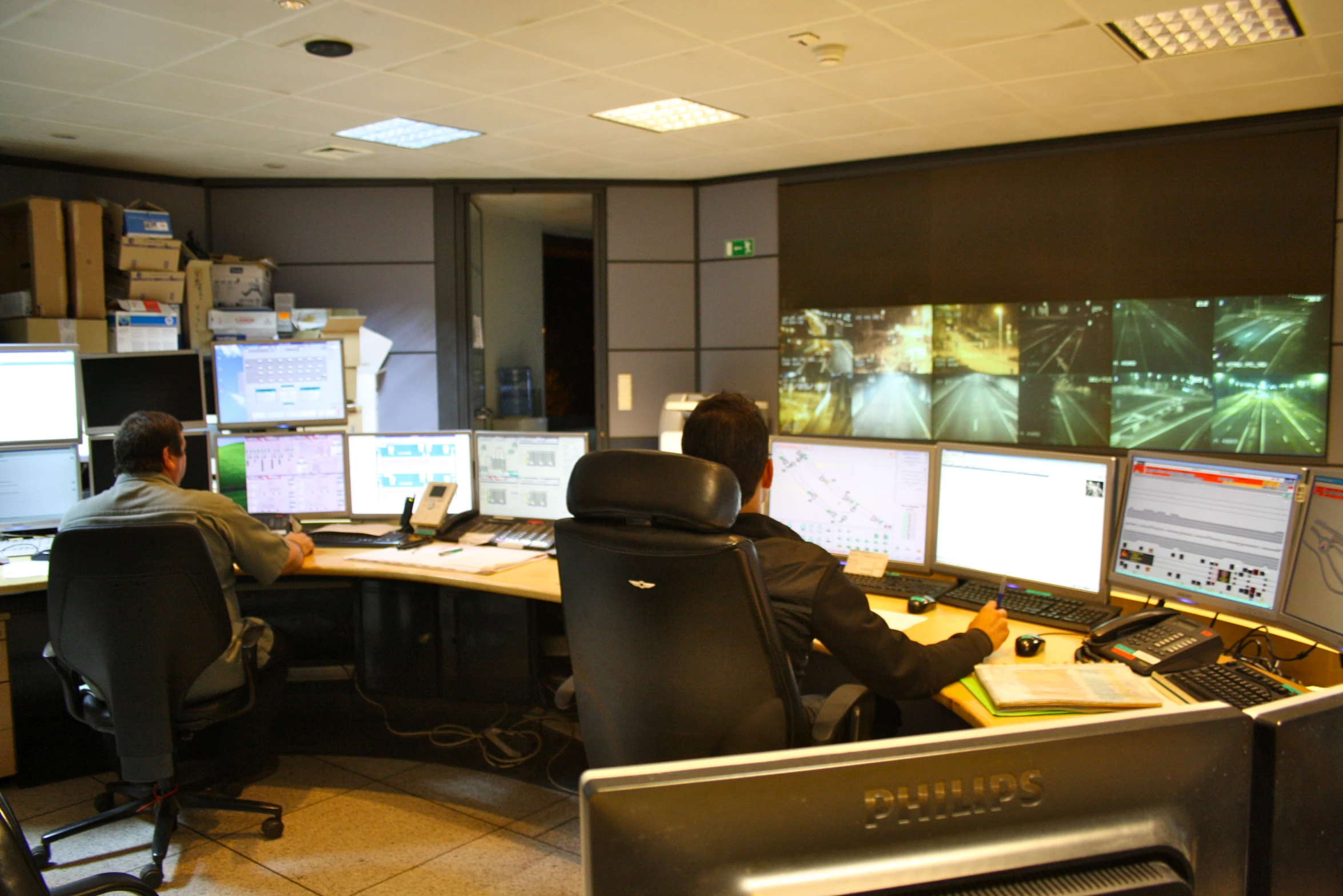 a control room with multiple monitors and a man sitting at his desk