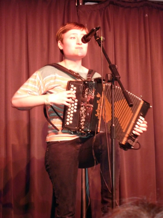 a man holding an accordion and standing next to a microphone