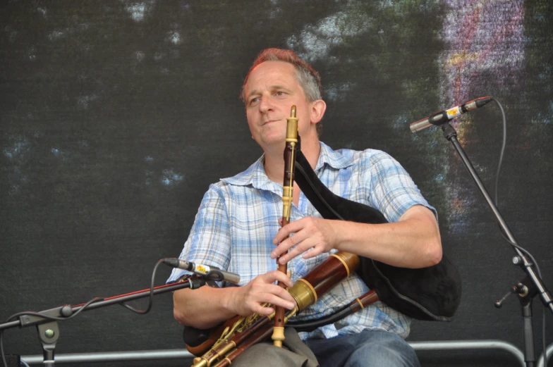 man with blue shirt and tan tie playing the trumpet