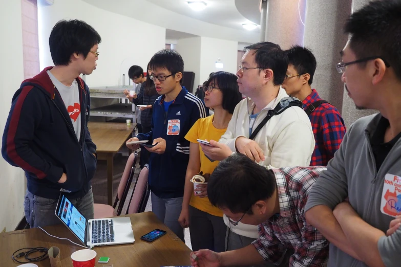 a group of young people looking at soing on a desk