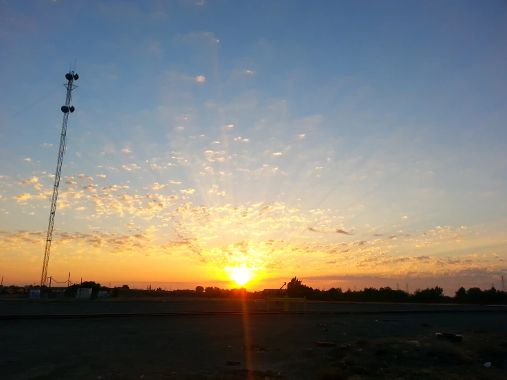 a sun setting over a cell tower and some other tall buildings