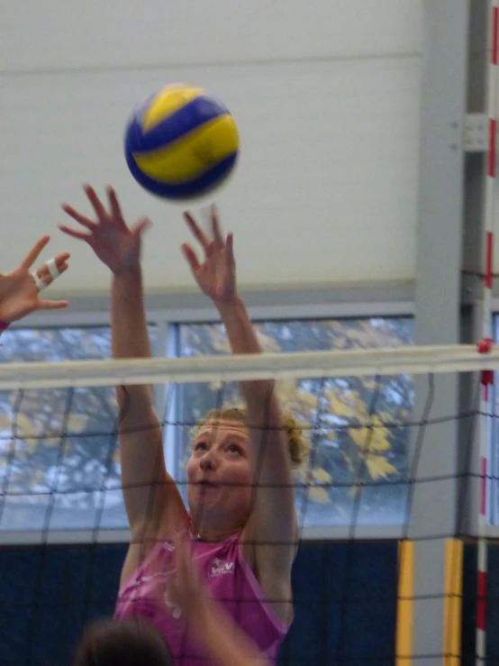 two s playing volleyball on an indoor court