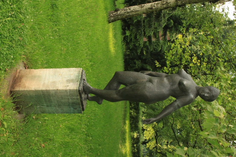 a statue stands on a pedestal in the grass