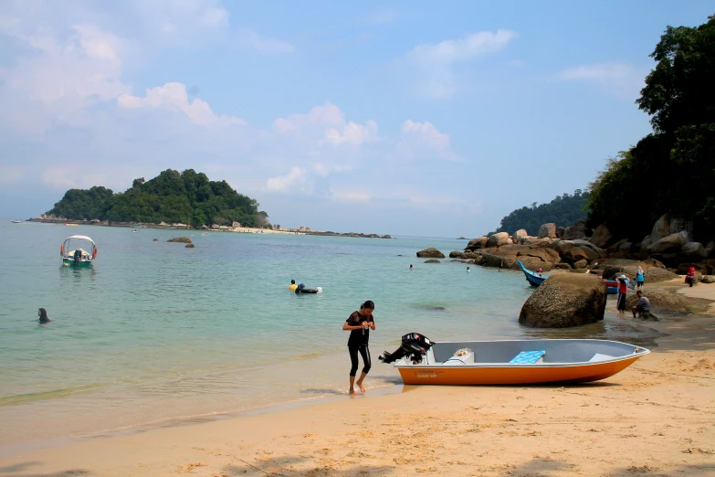 the young man is next to a boat by the beach