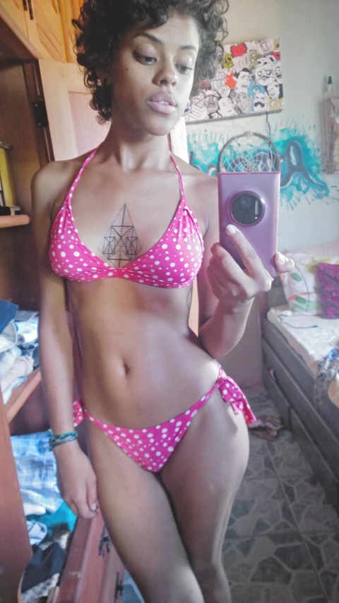 a woman in polka dot bikini and a cell phone taking selfie