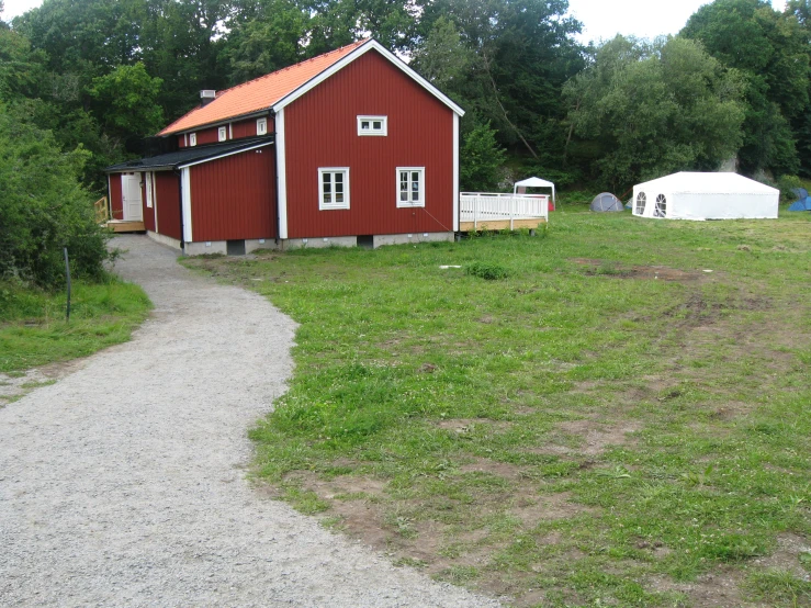 a red barn is in the middle of a dirt road