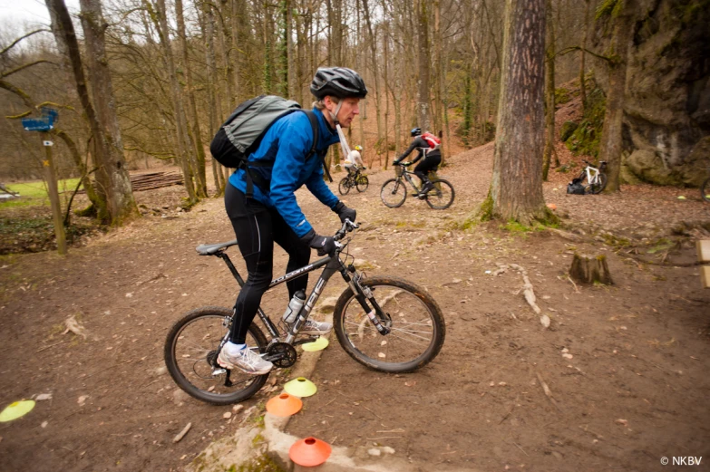 two bicyclists ride in the woods on their bicycles